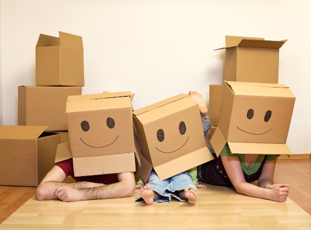 Smiley moving family concept - couple with a kid and lots of cardboard boxes